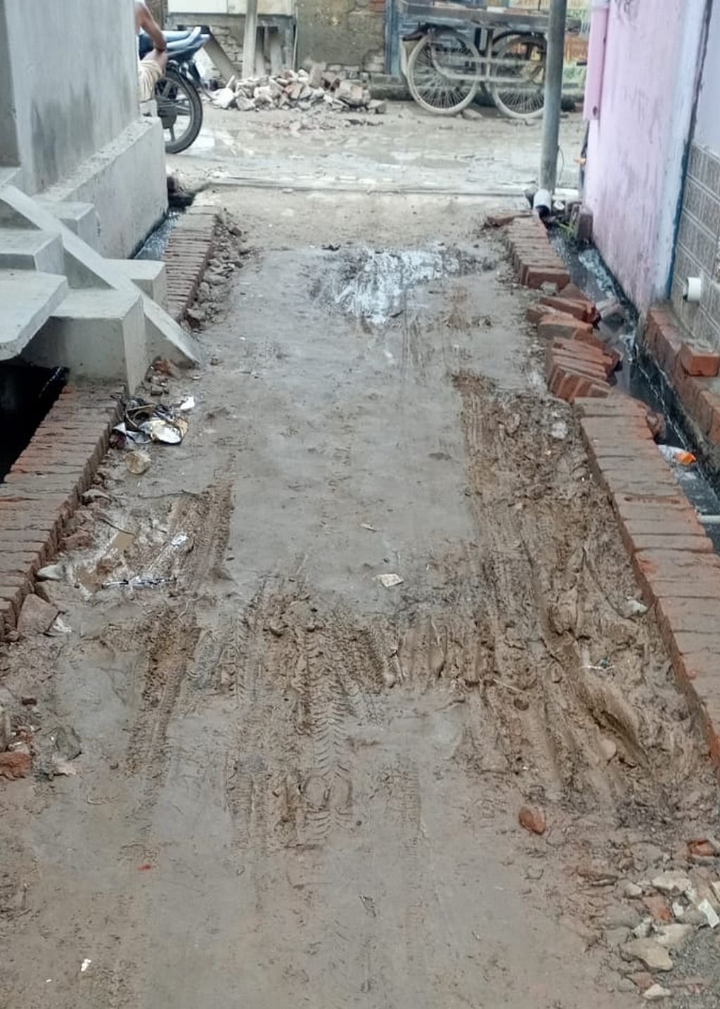 गली में ईंटे लगाकर छोड़ गया ठेकेदार, कीचड़ मे फिसलकर गिर रहे लोग